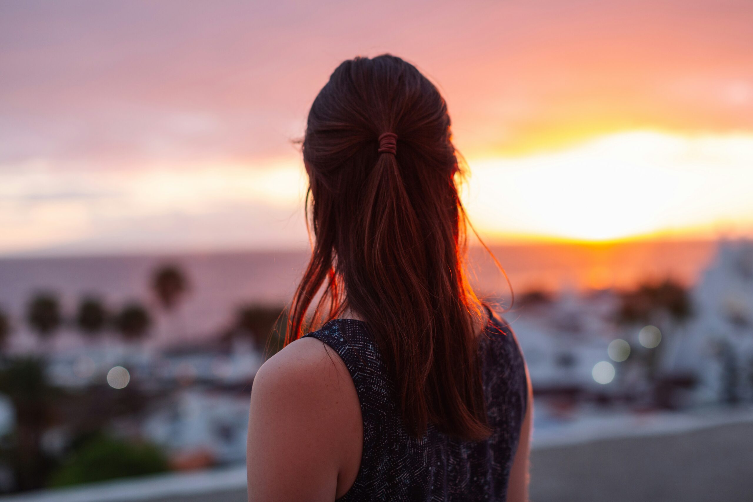 A woman standing on top of a roof looking at the sunset